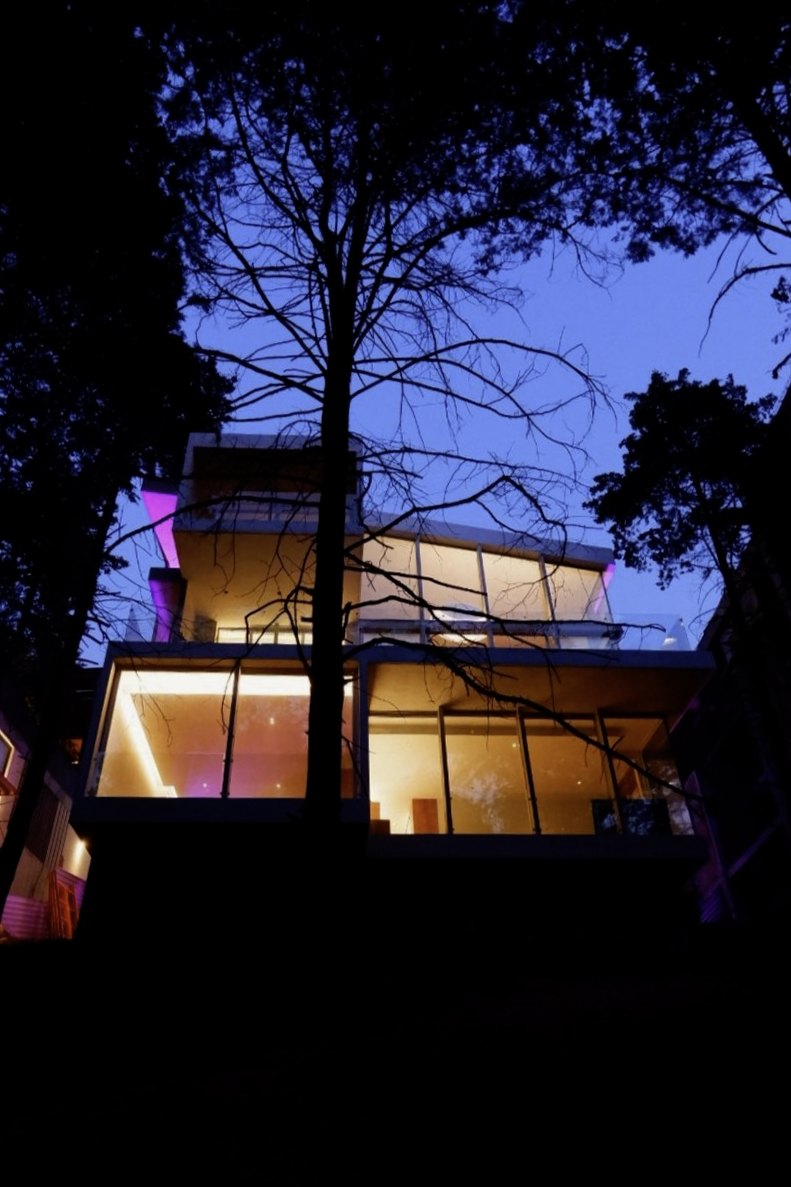 La casa encendida de noche entre los árboles