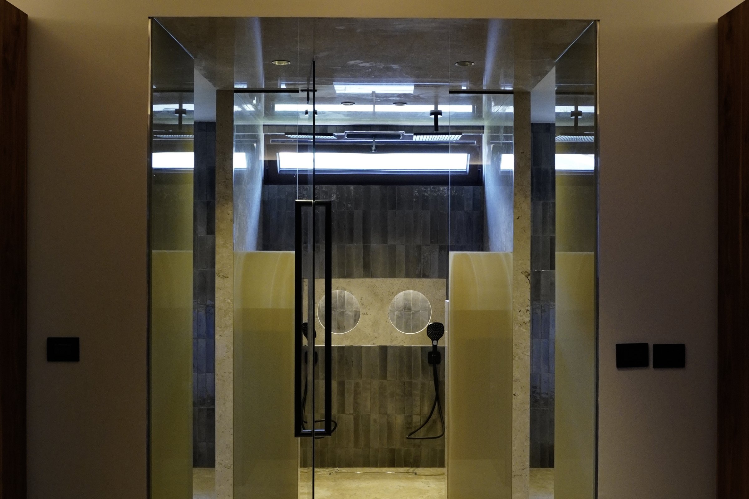 Baño con la mampara de cristal y los muros de piedra traslúcida
