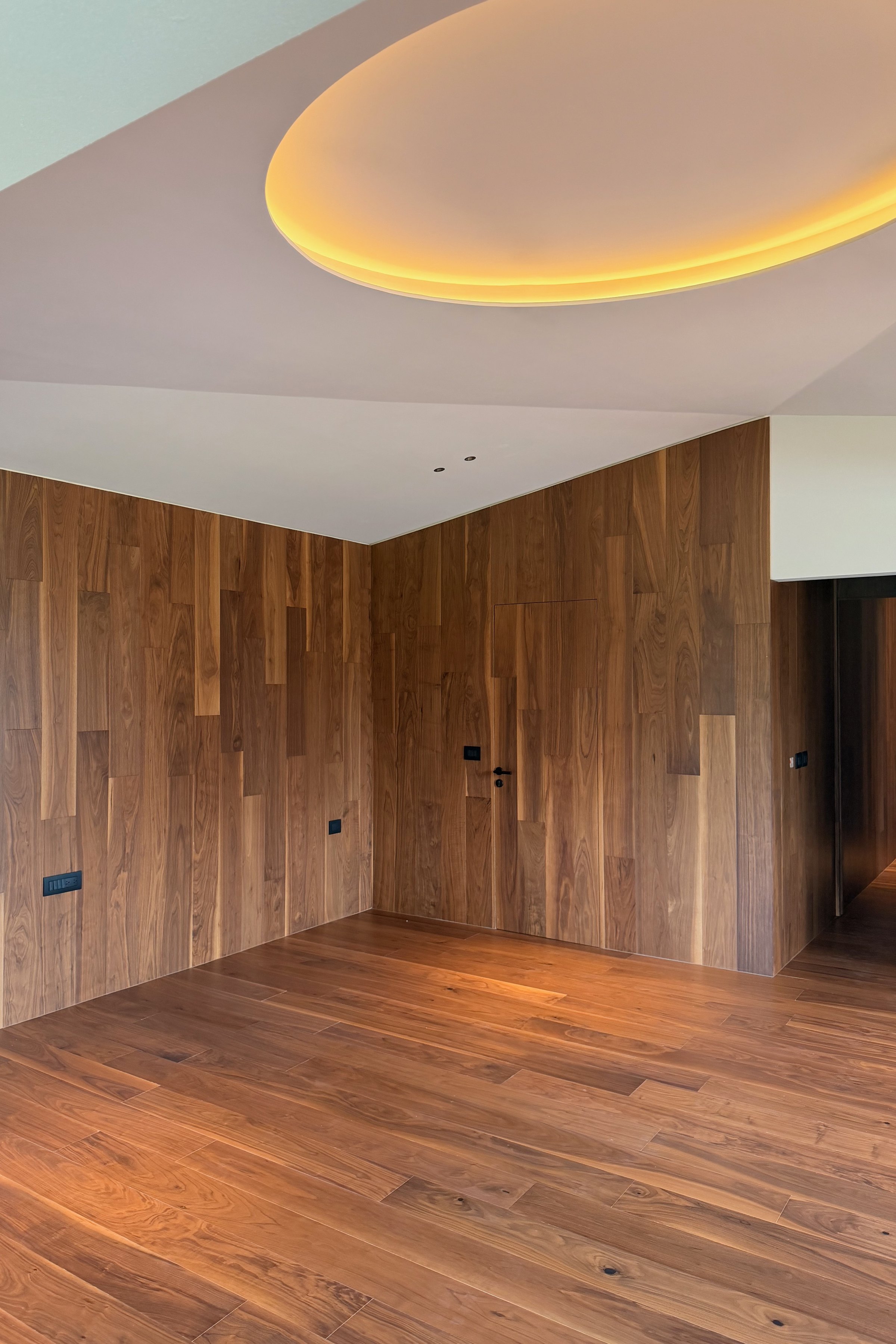 Habitación con el plafón circular iluminado y los muros de madera
