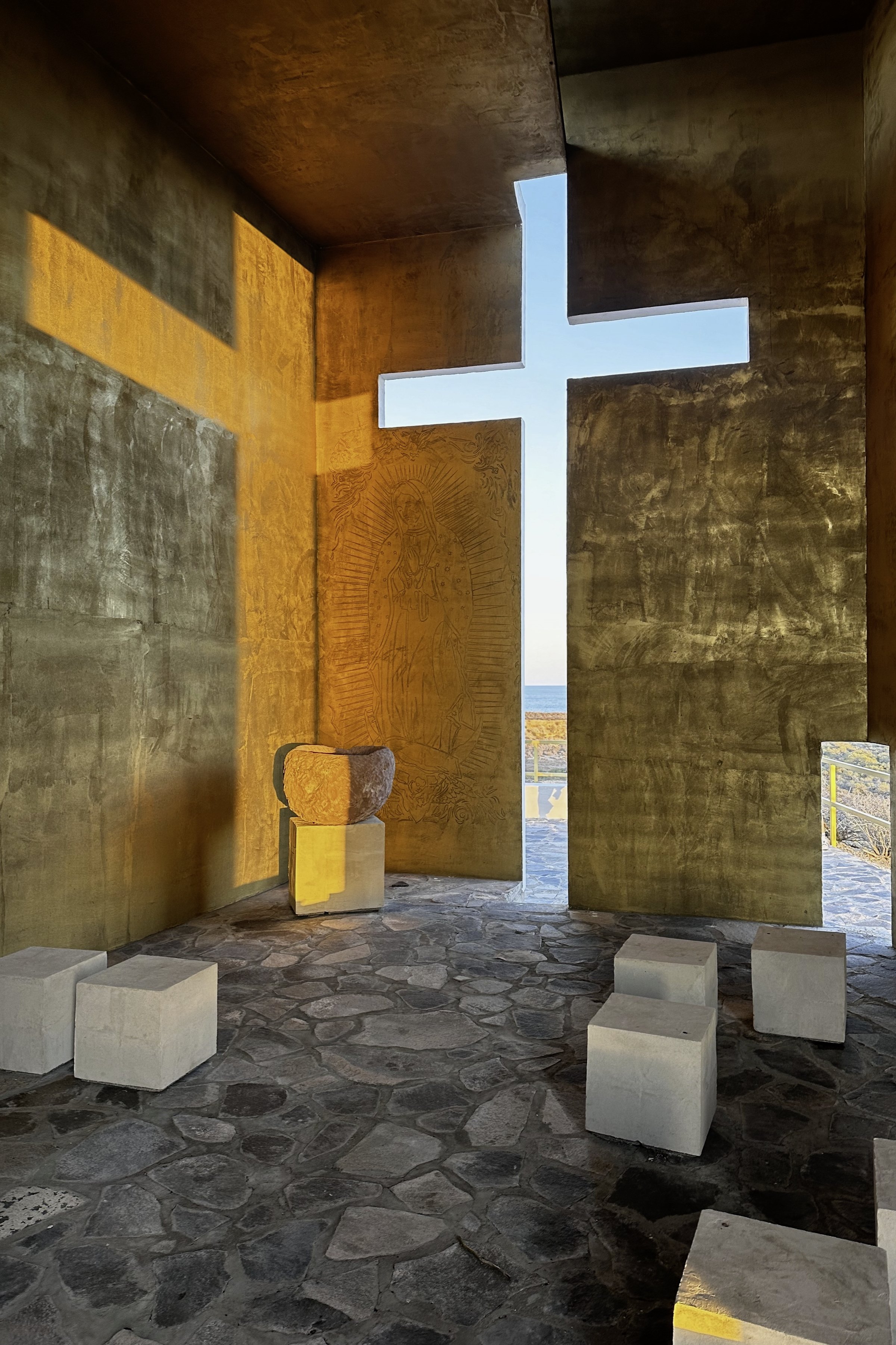 La cruz de luz cruzando el muro, con los bancos delante