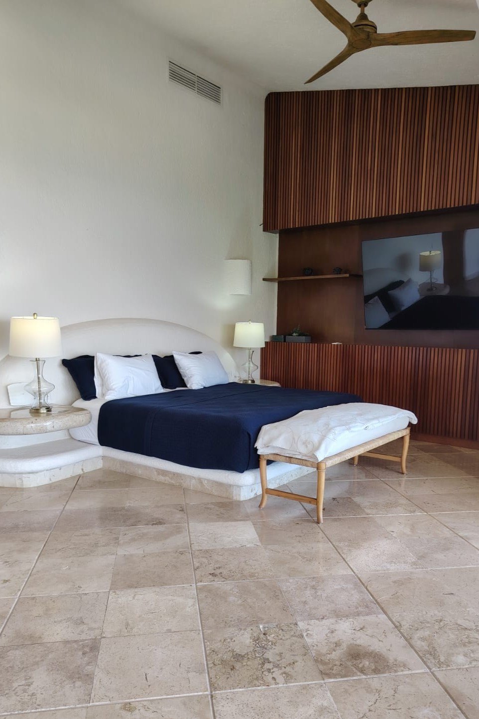 Recámara con el cabecero de madera y la cama vestida